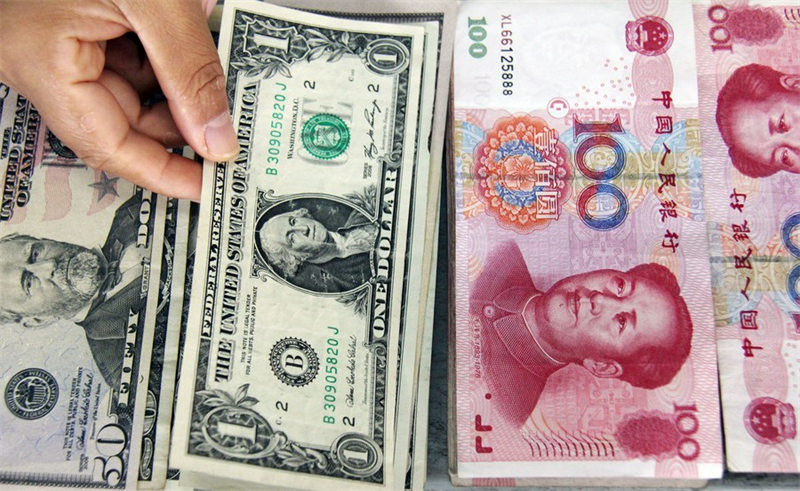 Picha inaonyesha karani akichagua noti ya dola kati ya noti za dola ya Marekani na Renminbi (RMB) kwenye benki moja huko Linyi, Shandong Mashariki mwa China. (Xinhua/Zhang Chunlei)