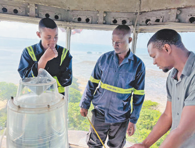 Wafanyakazi wa mradi wa kuchimbua matope kwenye njia ya majini ya Bandari ya Dar es Salaam wakibadilisha taa ya kuongoza meli za mnara katika Kisiwa cha Makatumbe.