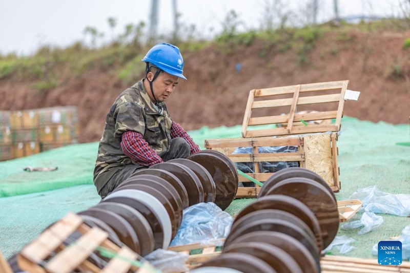 Mfanyakazi akifunga vihami kwenye sehemu ya ujenzi wa Mradi wa upitishaji umeme wa 1,000kV wa Sichuan-Chongqing katika Kitongoji cha Shaoyun cha eneo la Tongliang, Mji wa Chongqing, Kusini Magharibi mwa China, Machi 17, 2024.