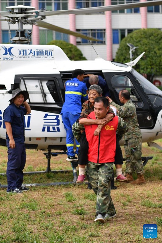 Mhudumu wa kujitolea akiwa amembeba bibi kizee kutoka kwenye helikopta katika shule ya sekondari huko Zixing, Mkoa wa Hunan, katikati mwa China, Julai 29, 2024. (Xinhua/Chen Zhenhai)